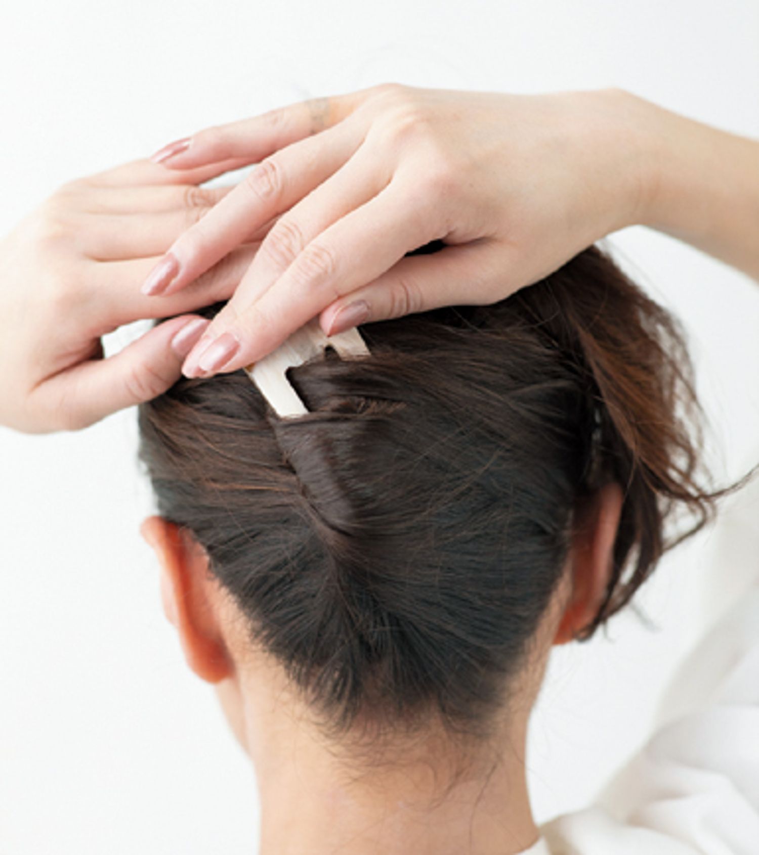 逆側に倒してねじり上げた側面に沿って、斜め下にかんざしを挿し込む。