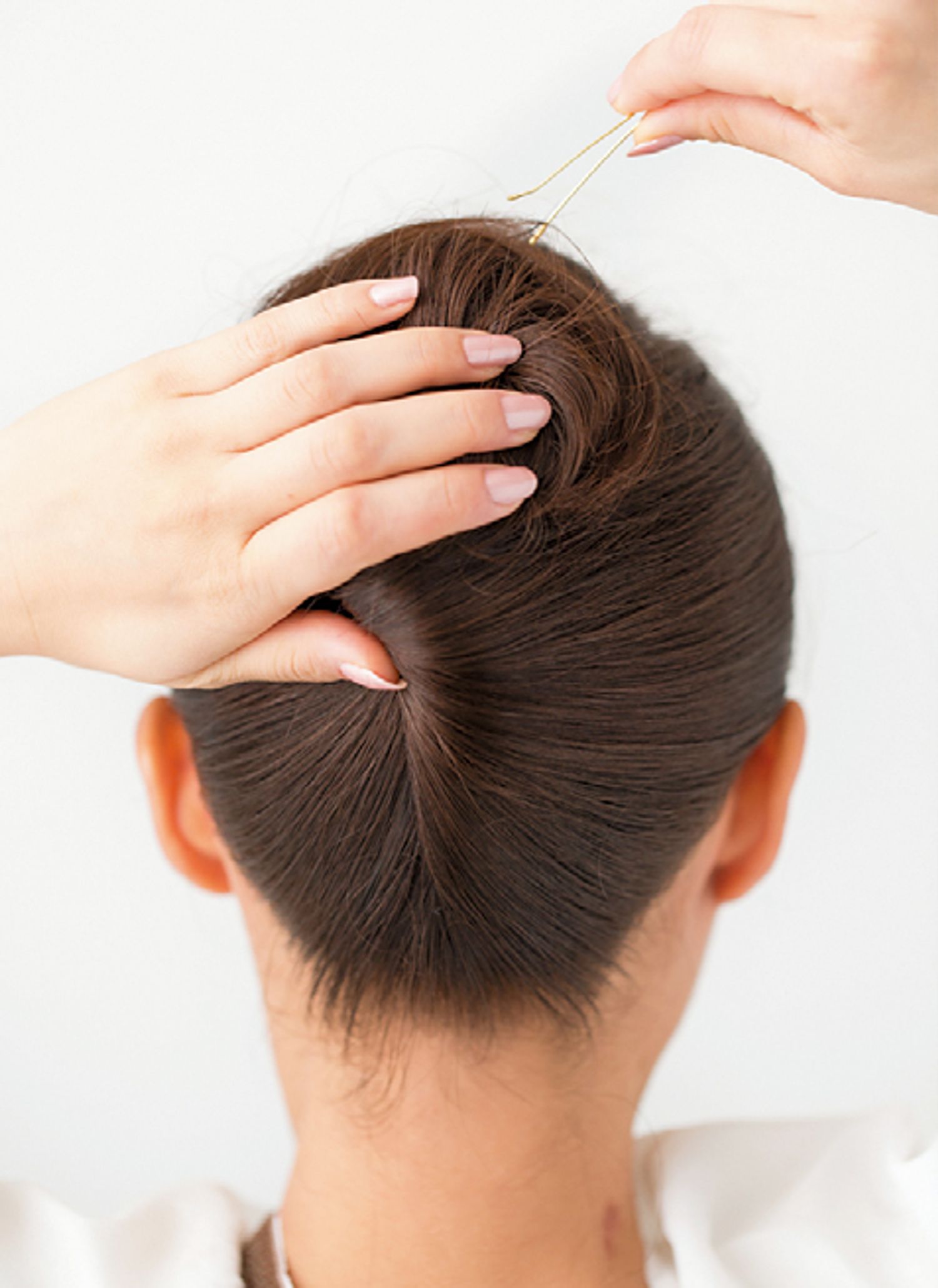 3　上に出た毛先は丸めてシニヨンにし、何ヶ所かピンでとめる。