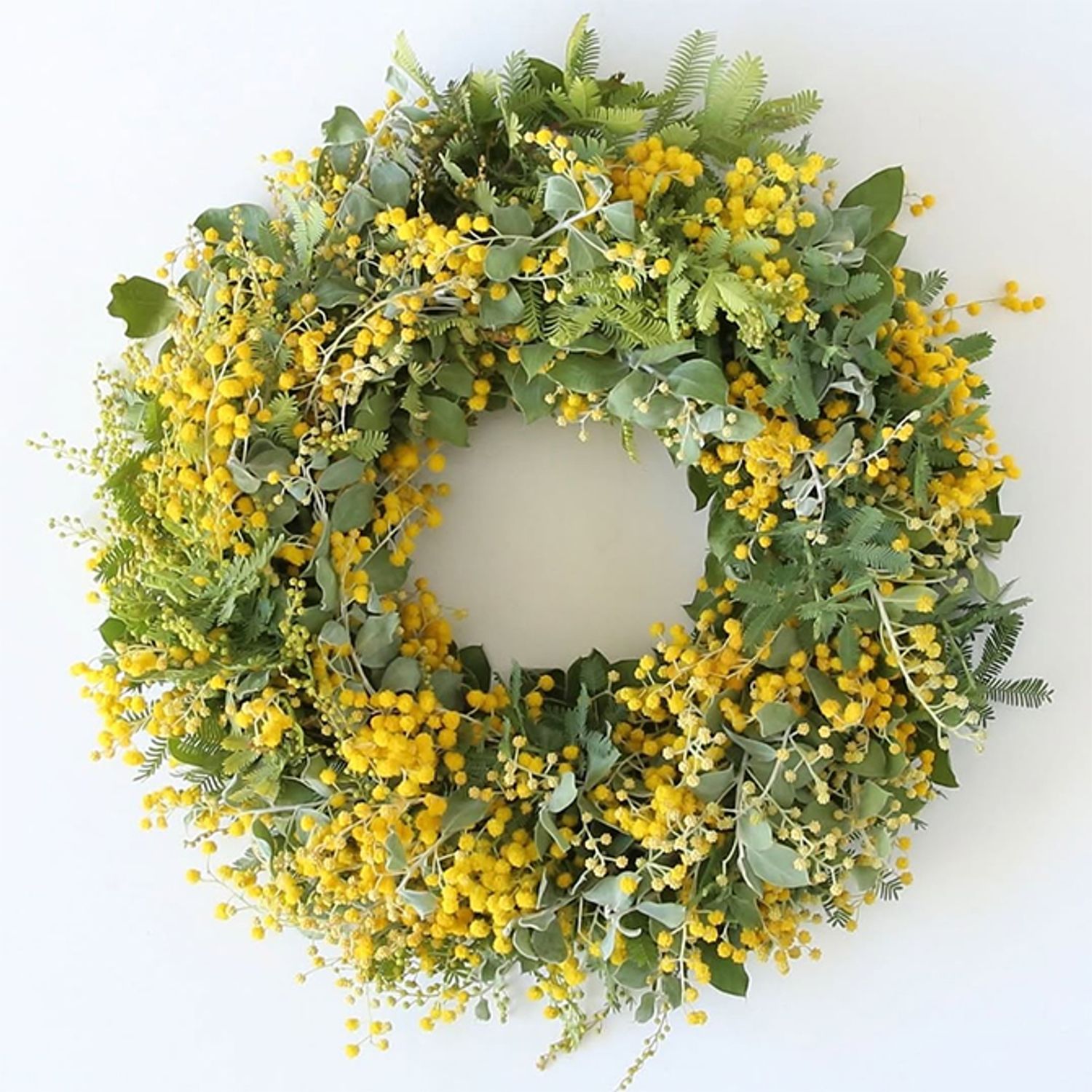 花は‘ミランドール’、葉はパールアカシアと‘オーレア’、と3種類のアカシアを使ったリースです。葉の形が異なり、より繊細で表情豊かな仕上がりになります。木のつるで編んだリースベース（約20cm）を利用。