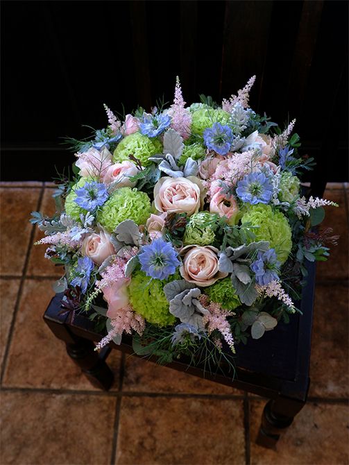 バラ‘シフォンベール’の少しクールなピンクに、ラナンキュラスの‘ちほの恋’と‘レオニャン’、アスチルベ‘ライトピンク’を合わせ、ニゲラ‘ミスジーキル’の水色と対比させたアレンジ。アスチルベのすっとした穂状がアクセントになります。ほかにリシアンサス‘アンバーダブルモヒート’、ダスティーミラー、アカシアなどを使用。