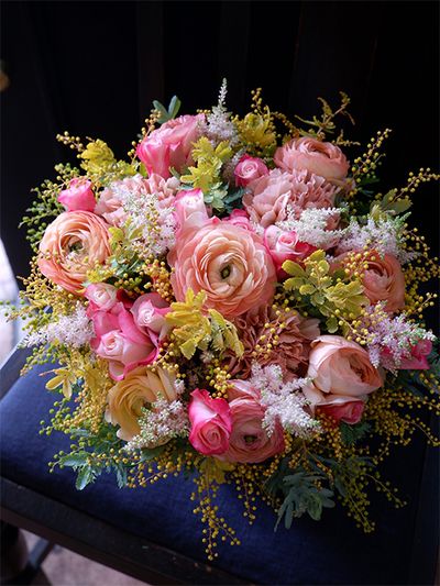 千葉で出産予定のお嫁さんへ、兵庫のお義母さまから癒やしの贈り花です。ラナンキュラス‘サルモネ’、バラ‘ストロベリーモンローウォーク’、アスチルベ‘ライトピンク’に、少しシックな花色のカーネーション‘レージェマロン’を加え、ほどよく華やかなアレンジに。金葉アカシアは花と花の間のクッションとしても使いやすい花材です。