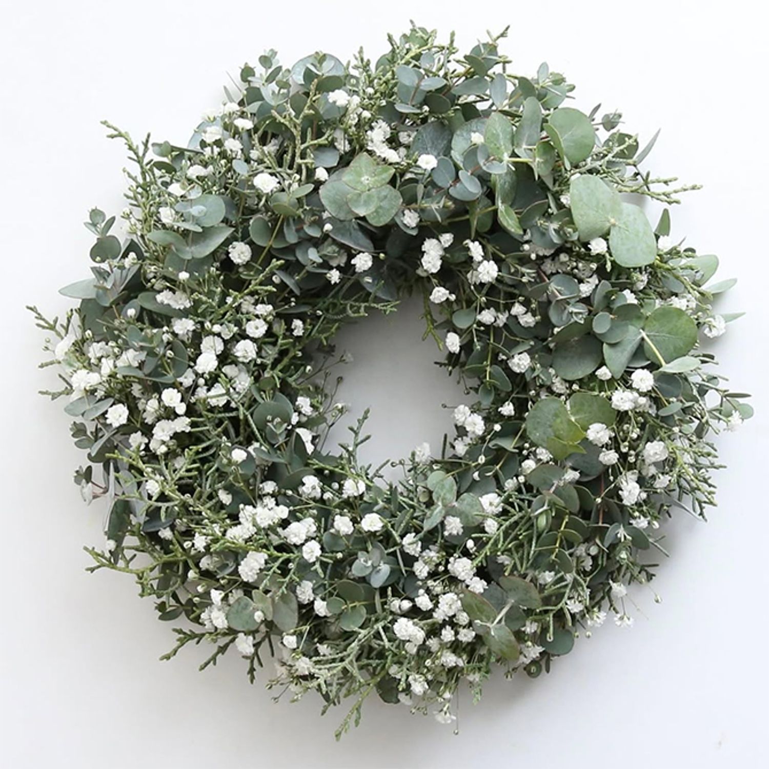 ユーカリ・グニーと‘銀世界’に、コニファー‘ブルーアイス’を加え、さわやかな雰囲気のリースに。ユーカリにはすっきりとした心地よい香りがあるのですが、’銀世界’はとくに香りが強く、‘銀世界’はさわやかで心地よい香りがして、制作しているときから気分がよくなります。木のつるで編んだリースベース（約20cm）を利用。