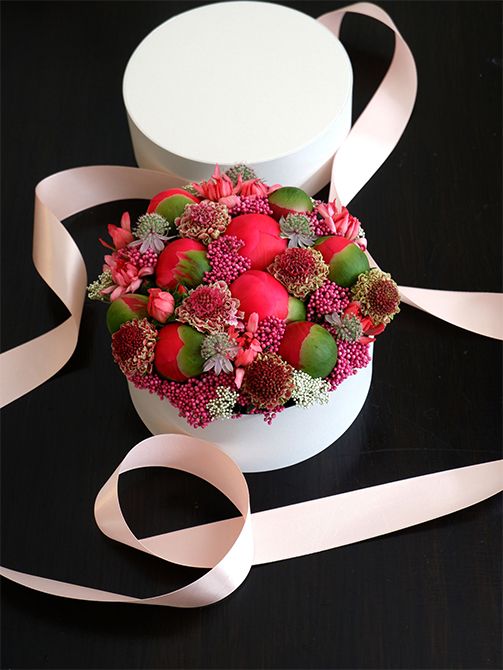 ライスフラワー‘マゼンタ’を使って、ボックスフラワーの贈り花を。ボール状の大きな蕾はシャクヤク‘コーラルチャーム’。スカビオサ‘コットンキャンディスクープ’も加え、すき間を埋めるようにライスフラワーやカーネーション‘ミニティアラ サーモン’、アストランティア‘フローレンス’を加えています。