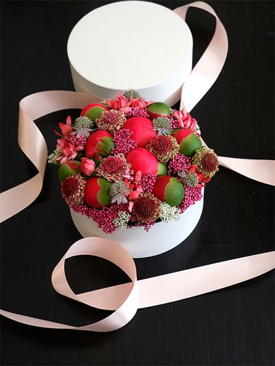 ライスフラワー‘マゼンタ’を使って、ボックスフラワーの贈り花を。ボール状の大きな蕾はシャクヤク‘コーラルチャーム’。スカビオサ‘コットンキャンディスクープ’も加え、すき間を埋めるようにライスフラワーやカーネーション‘ミニティアラ サーモン’、アストランティア‘フローレンス’を加えています。
