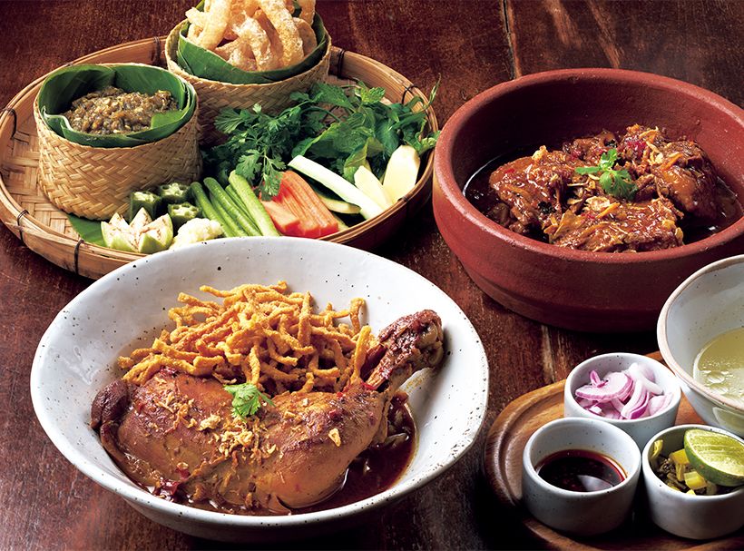 手前から、カオソーイガイ260バーツ、5時間煮込んだ豚肩肉のカレー煮込み390バーツ、生野菜や豚皮の揚げ物が添えられた青唐辛子のディップ、ナムプリックヌム190バーツ。