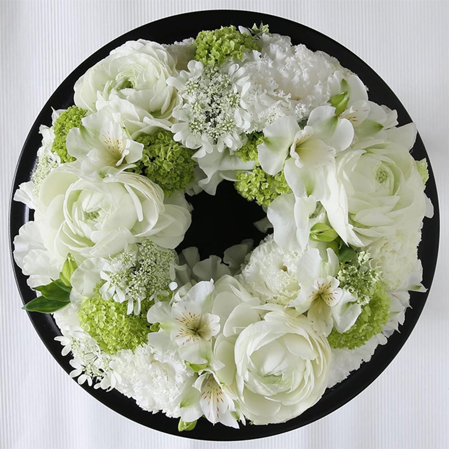 白と緑の色合わせで初夏のさわやかな気候を感じさせるリースに。白花はリシアンサス、ラナンキュラス、アルストロメリア、オルレアなど。淡い緑はビバーナム・スノーボールです。直径約20cmのフローラルフォームを使用。