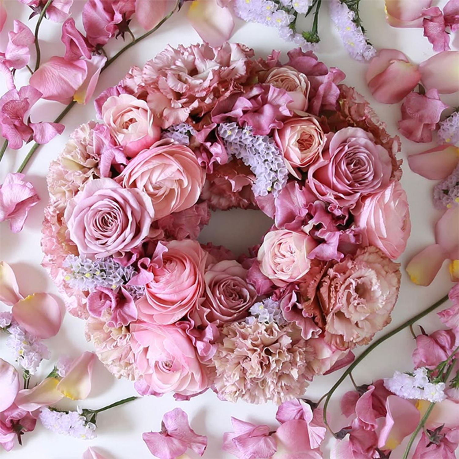 パステルピンクにくいみ系のピンクを加え、かわいらしさの中に大人っぽさもあるテーブルリースに。大輪のフリンジ咲きカーネーション‘シャララ ピコ’、同じような色合いのリシアンサスとバラ、そしてアクセントにごく淡い紫のスターチスを加えています。直径約20cmのフローラルフォームを使用。