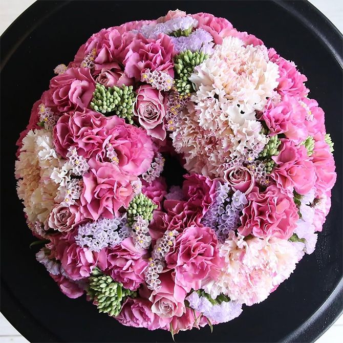 濃淡のピンクのカーネーションとバラを使い、メリハリのある表情に仕上げたリースです。淡いピンクは大輪カーネーション‘シャララ ピコ’。少しくすんだ濃いピンクのカーネーシヨンはスプレー咲きの‘モカスイート’。ほかにバラやスターチス、緑色のセダムなどを使っています。直径約20cmのフローラルフォームを使用。