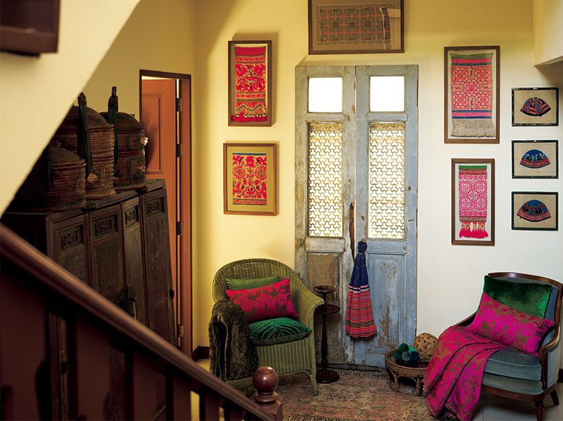 モン族の衣装や帽子はチーク材の額に入れ、階段下のスペースの壁に掛けた。イギリスのアンティークのソファと、ヴィヴィッドな色の布の取り合わせを、タイのものでありながら西洋の薫りを併せ持つジム トンプソンで誂えたクッションや布が中和させる。