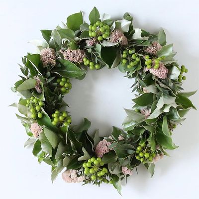 ワイヤーのリースベースを利用した緑のサンキライのフレッシュリースです。ほかに葉裏がシルバー色のギンバグミ、葉が小さなユーカリを使い、淡いピンクのスターチスをアクセントに加えています。いろいろな葉色に混じるサンキライの透明感ある実からフレッシュ感が伝わります。