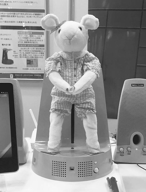 右・いとうさんが開発したロコモ予防介護支援ロボット「ロコピョン」。音声認識機能を用いて1日3回声かけをし、スクワット運動を促す。利用者が答えた回数だけロコピョンが一緒にスクワットを行う。画像認識システムによるフォームのチェックや見守りの機能も搭載。写真提供／いとうまい子さん