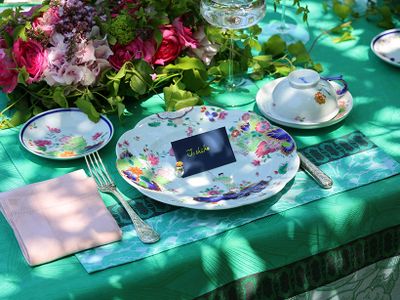 器に使われている色彩を食卓全体にリフレインした例。ネイビーをネームカードに、ピンクは花とナプキンに、そしてグリーンをテーブルクロスに。多色遣いの染錦を並べた食卓も、こうすれば美しく調和します。使用した器は深川製磁の「染錦絢爛草花絵」。