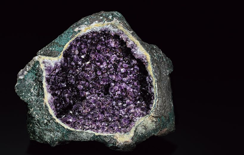 外側から見ただけではわからないが、中に空洞があり、割ると内部が水晶や瑪瑙（めのう）などの鉱物で覆われた石のことを「ジオード」（日本語で晶洞（しょうどう））という。こちらはアメシストの晶洞標本（ミュージアムパーク茨城県自然博物館所蔵）。実際のサイズは、幅95×奥ゆき75×高さ60センチとかなり大きい。このようなジオードから原石が採取される。