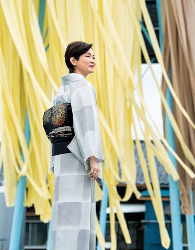 ｢手仕事の技とともに、この美しい光景も残したいものですね」と、昔ながらの櫓で反物を天日干しする様子を感慨深く見つめる藤間さん。お召しになった夏衣は、濃淡の染め疋田を市松取りに染めた小紋に、屋形船から花火を愛でる夏の風物詩を描いた染め帯。「錦や」で誂えたひと揃いが、目に涼やかさを映します。