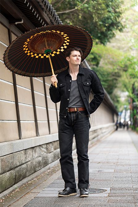 シックな柿渋の金沢和傘をブラックデニムの装いで楽しむ村雨さん。