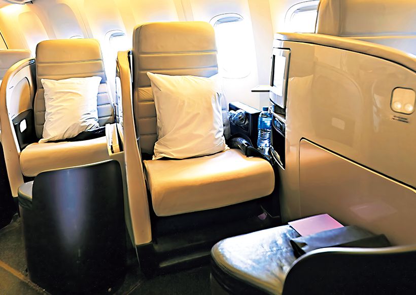 ビジネス・プレミアのシートは、通路に向かって斜めに座席がレイアウト。足もとにオットマンが配され足を伸ばすことができて快適。夜はマットレス、枕、掛け布団を備えたフルフラットベッドに早変わり。