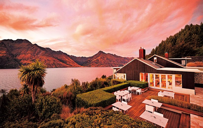 早朝、朝焼けが広がり、山と湖水 の色が赤く染まったマタカウロッジ。2010年にロバートソン家がワカティプ湖北岸に創設後、オーナーはそのままに2023年12月からローズウッドがホテルマネジメントを始めた。湖岸に沿って低層の客室が建てられ、風景に溶け込む理想的な佇まいとなっている。手前はレストランやロビーが入ったメイン棟。