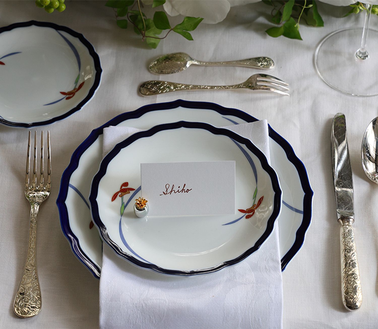 香蘭社のオーキッドレースのディナーシリーズの器を使って。瑠璃色の縁が料理を引き立て、白一色のテーブルコーディネートのアクセントにも。