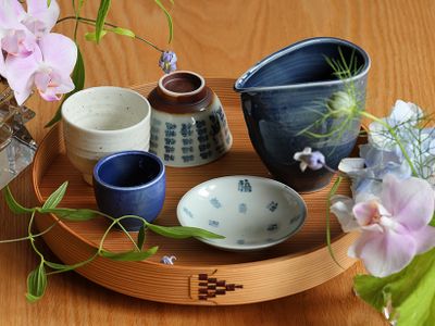 木目のテーブルと博多曲物の通い盆の上に、陶祖李参平窯の器を並べて。