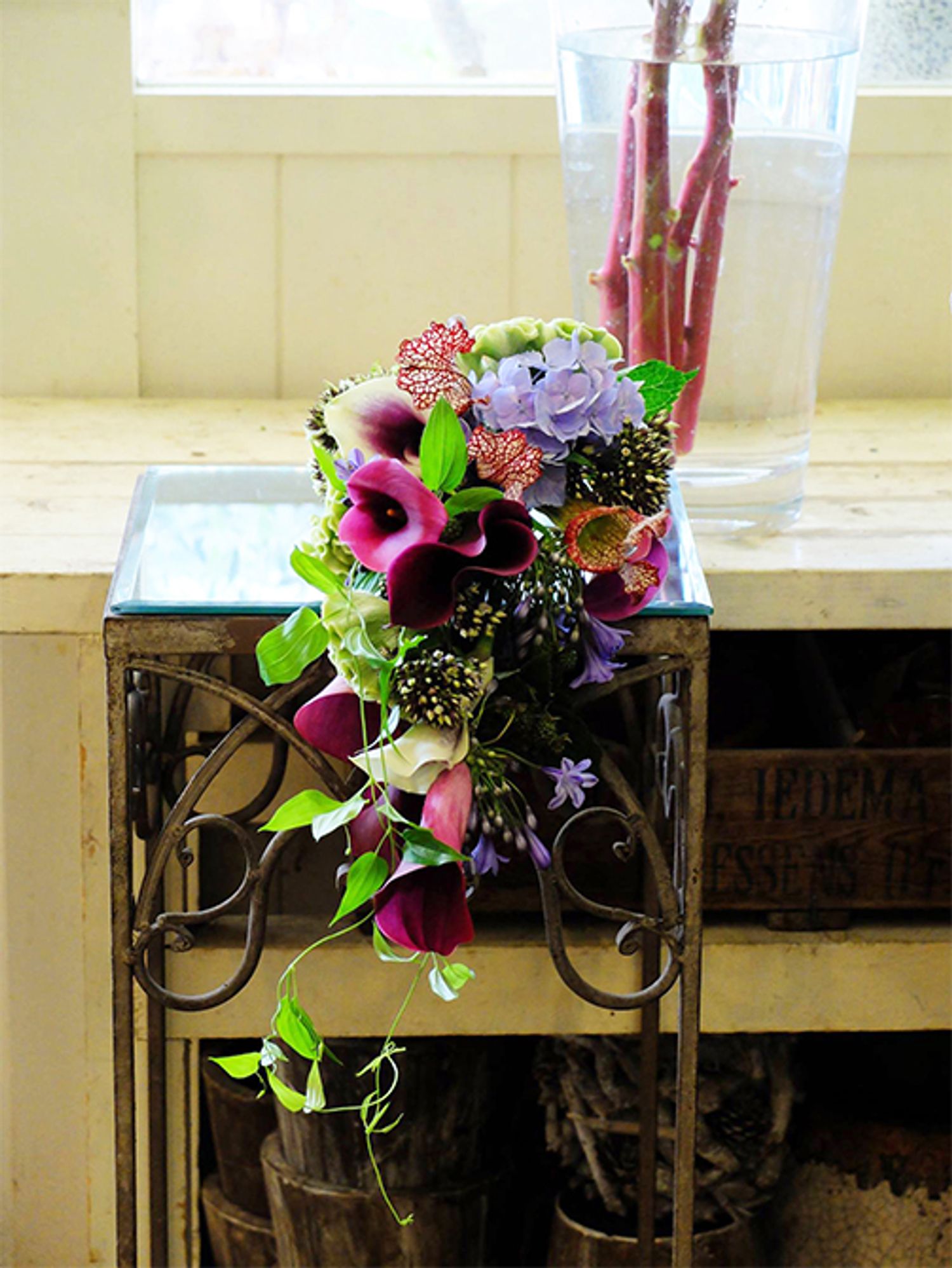 アガパンサス‘シビルハートン’は、花色は淡い青紫ですが、花柄が少し黒みを帯びているのが魅力的な品種です。それを利用して、大人っぽい雰囲気のウエディングブーケを制作しました。カラーの‘キャプテン プロミス’と‘ピカソ’、‘ホットチョコレート’をメインに、網目模様が個性的な食虫植物のサラセニア、アジサイ‘マジカルトパーズ ブルー’、ケイトウ‘アスカセレクト グリーン’、フロックス‘ミスティックグリーン’、ブラックベリー、リキュウソウなど、種類を豊富に使っています。