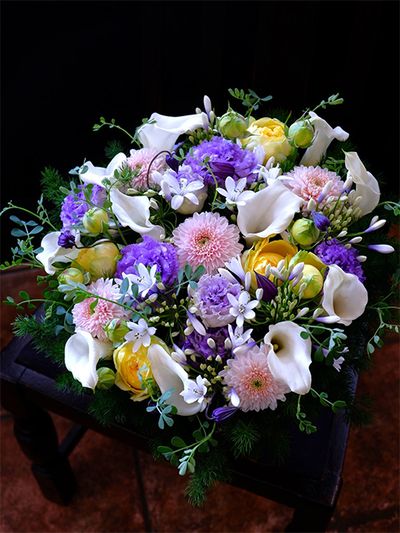 マム、リシアンサス、バラ、カラーなどを合わせた清涼感あるアレンジです。大きな花をまとめ役がアガパンサス‘ツイスター’。正面から見ると白い星形、横から見ると根元が青く染まっているのがわかります。マムは‘セイオペラ ピンク’、リシアンサスは‘NFラベンダー’と‘ボヤージュ ブルーシェイク’、バラは‘カタリナ’、カラーは‘ホワイトチョコレート’を使用・ほかにクレマチス‘篭口’、コロニラなどを使用しています。