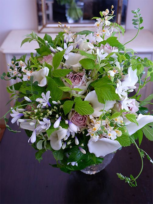  アガパンサス‘ツイスター’やカラー‘ホワイトチョコレート’など、白い花の中に、アンティーク感を醸すくすんだピンクのバラ‘ラピスヴェール’を加えたブーケです。くすみカラーを加えると、白がきりっと際立ちます。‘ツイスター’の花の根元の青紫がアクセントになり、さらに涼しげな印象に。ほかにオンシジウム‘サマースノー’、コロニラ、フランボワーズなどを使用。