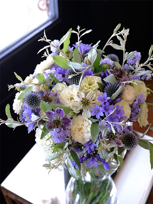 日々がんばっている奥様へ、ご主人から感謝の気持ちを込めた贈り花です。アガパンサス‘ゼラトーマス’をはじめ、この時期のブルーと白の花を集めて気持ちが癒やされるナチュラルなブーケを作りました。青花はルリタマアザミ‘ベッチーズブルー’とスターチス‘アイスブルー’、白花はバラ‘グリーンアイス’とニゲラ‘デルフトブルー’を選びました。ロシアンオリーブのシルバーリーフをたっぷりあしらって。