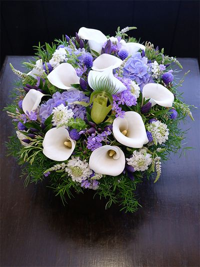 大阪の友人に夏の贈り花を。カラー‘サッポロ’とスカビオサ‘スクープ ホワイト’の白花にに、リンドウ‘FIブルー’、染めのセンニチコウ‘ブルー’、アジサイ‘アンティークブルー’、ラペイロージアの青花を合わせた涼しげなアレンジに。中心にパフィオペディルム‘クレアドルーン’を加えてアクセントにしました。「南原農園」さんのアスパラガス・スプレンゲリーとアップルミントをたっぷりあしらうと、よりクールでナチュラルな印象に。