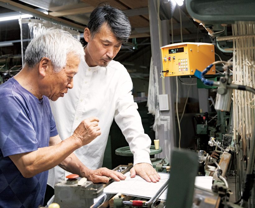 自社工場で製織の様子を確認する民谷さん（右）。織り手の吉岡正次さん（左）はこの道55年の大ベテランで、創業当時から民谷螺鈿に携わっている。