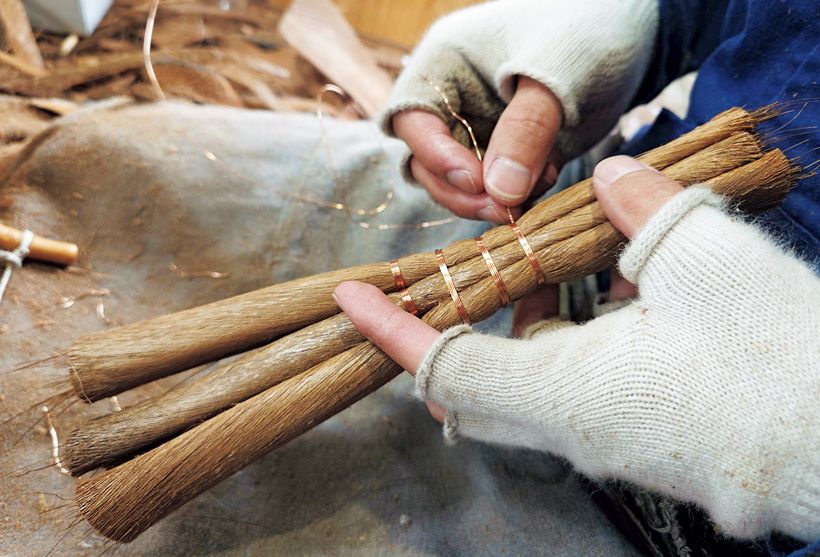 箒の柄の先には棕櫚の木の繊維を束ねた「玉」が銅線で丁寧に巻かれ、結ばれている。