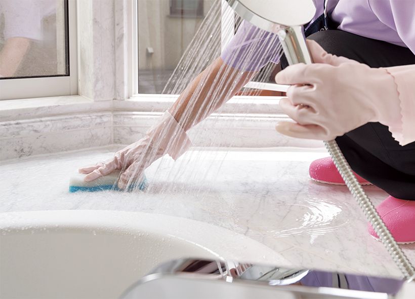 大きな窓のある白い浴室は外光の加減で汚れが目立ちやすいもの。困り事である大理石の水アカは、タイル面にはスポンジ、目地にはブラシと、道具を使い分けながら、洗剤を使わずに磨き取ります。また、シャワーヘッドのカルキ汚れは、中性洗剤をブラシにつけて洗い、吸水クロスで丁寧に拭き上げます。