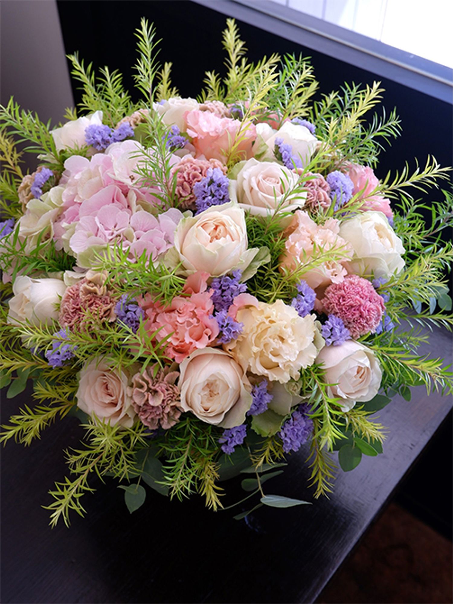 お友達の結婚祝いに、優しいピンク色を集めたアレンジをお届けしました。バラの‘シフォンベール’と‘デザート’、リシアンサス‘プリマアプリコット’。ケイトウ‘プティフルーツ フェアリーローズ’のニュアンスのあるピンクがアレンジを大人っぽい表情に。スターチス‘アイスブルー’をアクセントに加えると、さらにピンクの華やかさが引き立ちます。