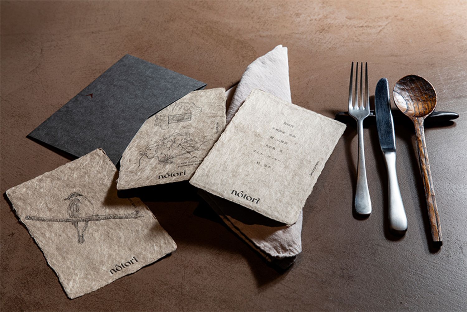 山梨県身延町の名産・西嶋和紙を、ヤマブドウやドクダミで染めた品書き。兄の茂一郎さんが描いたキビタキがゲストを迎える。