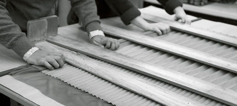 プリーツの型紙は段ボール素材で不透明なため、中の生地のズレを感じ取ったり、余分な厚みを見極めるには、まさに職人の長年の経験が不可欠。サンアコーディオンプリーツを閉じる作業では、2人の職人が完全に呼吸を合わせて作業をする必要があります。©le19M-Anne Combaz