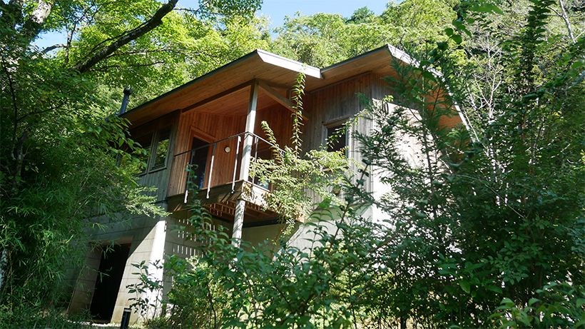 丘に建つ10号棟の外観。生い茂る草木の中に佇む。2階にリビングとテラス、寝室などがある。