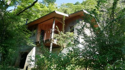 丘に建つ10号棟の外観。生い茂る草木の中に佇む。2階にリビングとテラス、寝室などがある。
