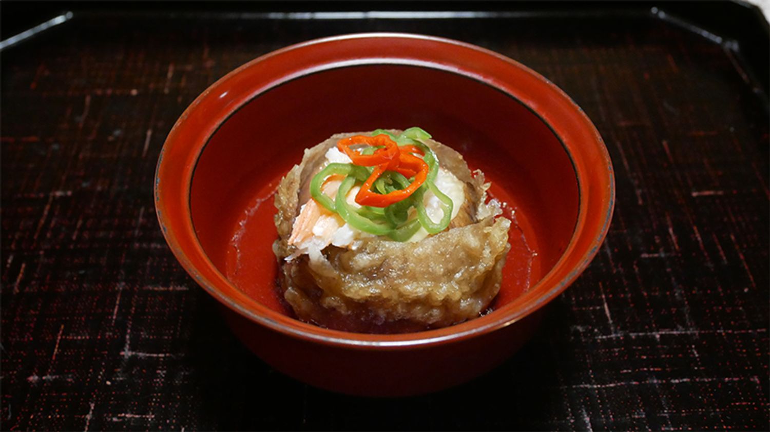 丸ごと1つをそのまま揚げたいちじくにかにをのせ、出汁をかけた「いちじく揚げ出汁 かに身 輪万願寺 煎りだし」。とろりと甘みのあるいちじくの果肉と、かに、塩味がきいたやさしい味わいの出汁、そして万願寺唐辛子の香りが繊細に組み合わされる。