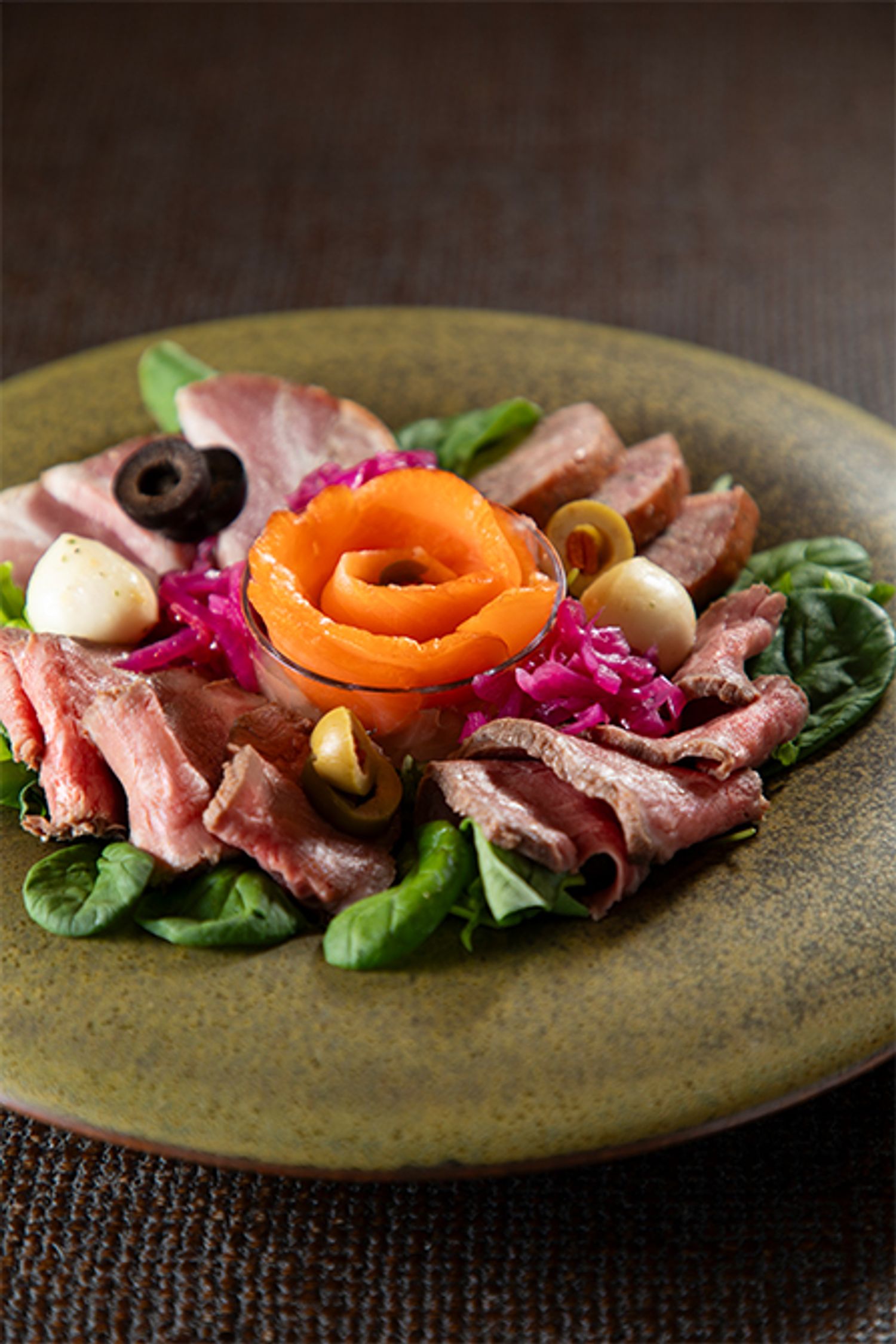 「三段おせち」の弐の重に入ったローストビーフは薄切りにして食卓にだすとより華やかに。同じ重に入っているスモークサーモン、オリーブ、モッツアレラチーズなどを一緒に合わせます。