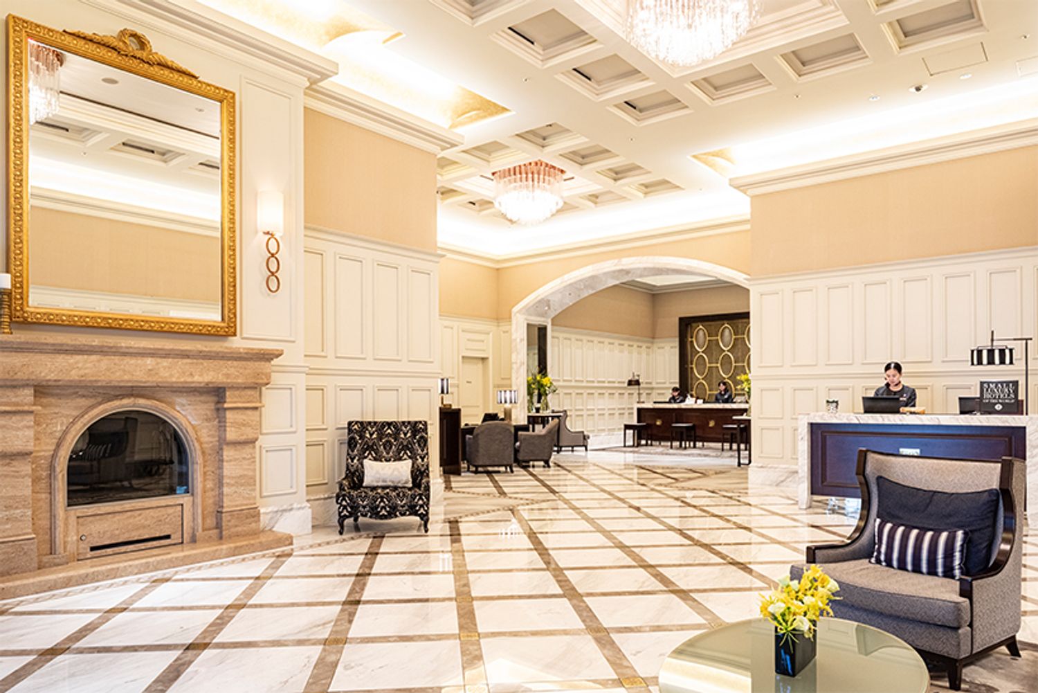 駅前の喧騒が嘘のように、ゆっくりと時が流れるフロント。白とゴールドのエレガントな空間がゲストを包み込む。