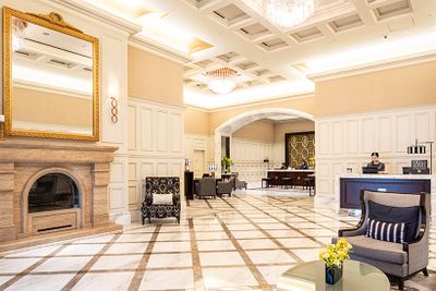 駅前の喧騒が嘘のように、ゆっくりと時が流れるフロント。白とゴールドのエレガントな空間がゲストを包み込む。