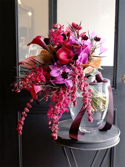 深いピンクの花を集めた秋のブーケ。なかでも目をひくのは、ブーケに流れを生み出す濃いシンフォリカルポス‘ワイルドゼロ’だと思います。美しい濃いピンクの小さな実がぎゅっと詰まって連なる枝は本当に魅力的。ほかにカラー‘トーキョー’、ランのバンダとレナンセラ‘バンコクビューティーピンク’、アンスリウムの‘モナリザ’と‘テラ’、チョコレートコスモス、蕾ガーベラの‘ボレロネイロネイロ’、アゴニス‘ブラックテイル’などを使用。個性的な花を少しずつ使い、ほかにはないオリジナルな雰囲気に仕上げました。