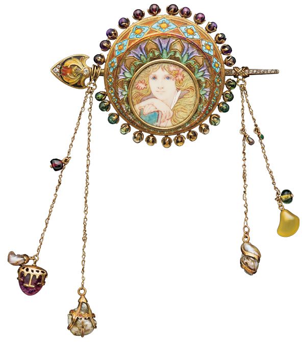 フレンチ・アール・ヌーヴォーのエナメルとパール、宝石をセットしたイエロー・ゴールドのコルサージュ・オーナメント。アルフォンス・ミュシャのデザインによるジョルジュ・フーケ製作のもので、その円盤にはミュシャによってヴェラム（子牛の革）に描かれた乙女の頭像と羽ペンを持つ女性像が収められ、4本のチェーンがさまざまな宝石を吊り下げている。1900年頃、フランス