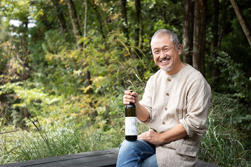 「98wines」代表の平山繁之さん。手にするのは2024年「芒（NOGI）」の白（3850円）。「自分の造るワインの中に、“一番おすすめ”や“一番好き”などといった優劣はない。場所の違い、ぶどうの品種の違いが、異なる味わいのワインを造り出す、ただそれだけです」。