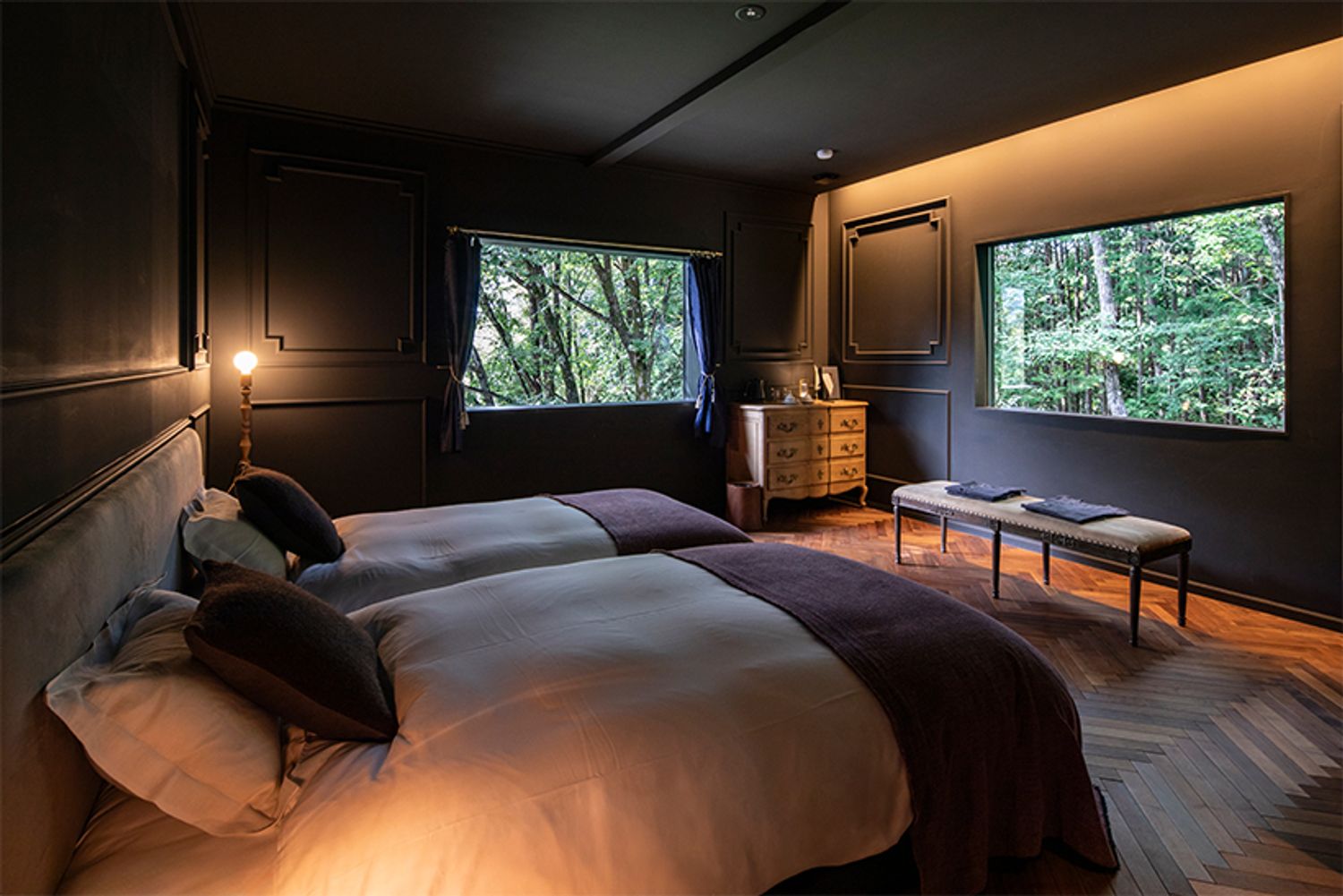 「玄-GEN-」の部屋。ピクチャーウィンドウから、豊かな森を望む。パジャマやアメニティは、山梨県の織物など地域で作られる上質なものを採用している。