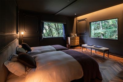 「玄-GEN-」の部屋。ピクチャーウィンドウから、豊かな森を望む。パジャマやアメニティは、山梨県の織物など地域で作られる上質なものを採用している。