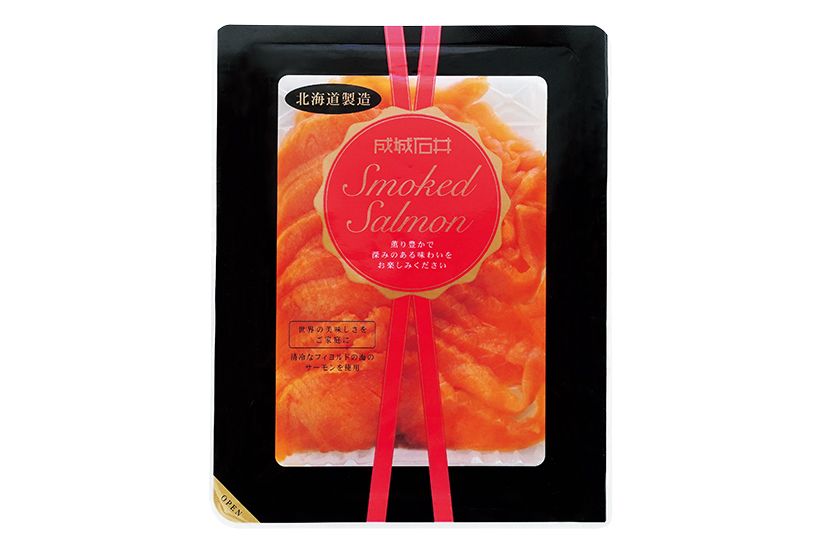 厳しい選別基準をクリアしたチリ産の トラウトサーモンを、調味液に3〜4日 間漬け込んで、長時間乾燥を行うことで うまみを凝縮。桜を中心としたチップを 用いて直火方法で燻製したやさしい風 味と、厚さ約3㍉にスライスした口当た りのよさが魅力。成城石井 スモークサー モンスライス130㌘1502円（※一部店舗 では110㌘1178 円 にて販売）