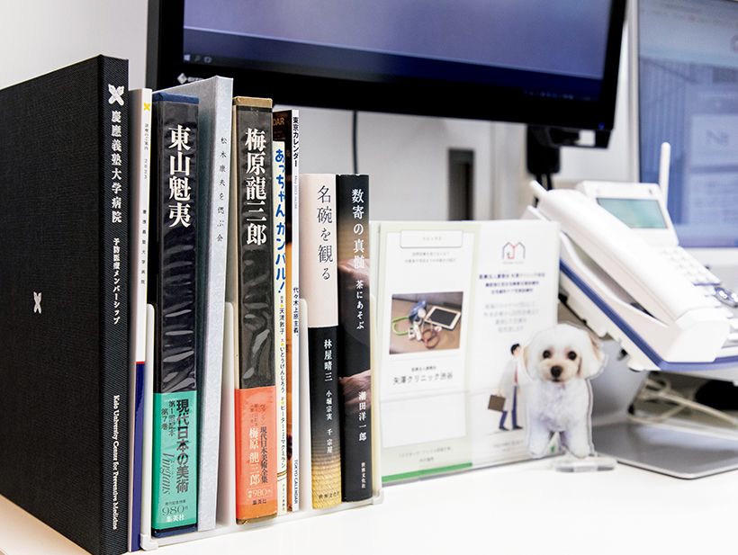デスク上には、愛犬のアクリルスタンド、趣味の茶道や絵画、短歌の本が置かれ、患者との会話のきっかけにもなる。