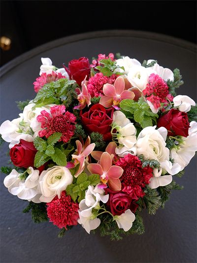 目上の方への贈り花におすすめの、赤バラとランの組み合わせです。バラは‘ブリランテ’、ランはファレノプシス‘パフューム’。立体的な花形のバラの中にファレノプシスを加えると、ひらひらと軽やかに舞っているようにも見えます。ほかにスカビオサ‘プリエルージュ’、ラナンキュラス‘雪てまり’、宿根スイートピー、スペアミントなどを使用。