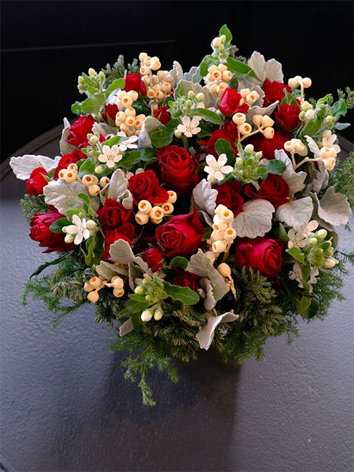 気品も感じさせる赤バラ‘ブリランテ’と‘ルビーブリリア’を使ったアレンジ。アクセントに加えた小さな白花はオキシペタルム‘マーブルホワイト’。赤×白×緑のクリスマスカラーですが、ユーカリの実のアンバーナッツのかわいらしい形、優しい色合いが加わるとぐっと個性的な雰囲気になります。ほかにダスティーミラー、コニファーを使用。