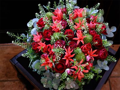 赤バラの‘ブリランテ’と‘フリューレット’の組み合わせですが、朱赤のダイヤモンドリリー‘スカーレット’を加えると、より赤が印象的に。花色が強くなりすぎないよう、緑のガーベラ‘みころん’、タラスピオファリムの優しいグリーンとシルバーリーフのユーカリで調和しています。